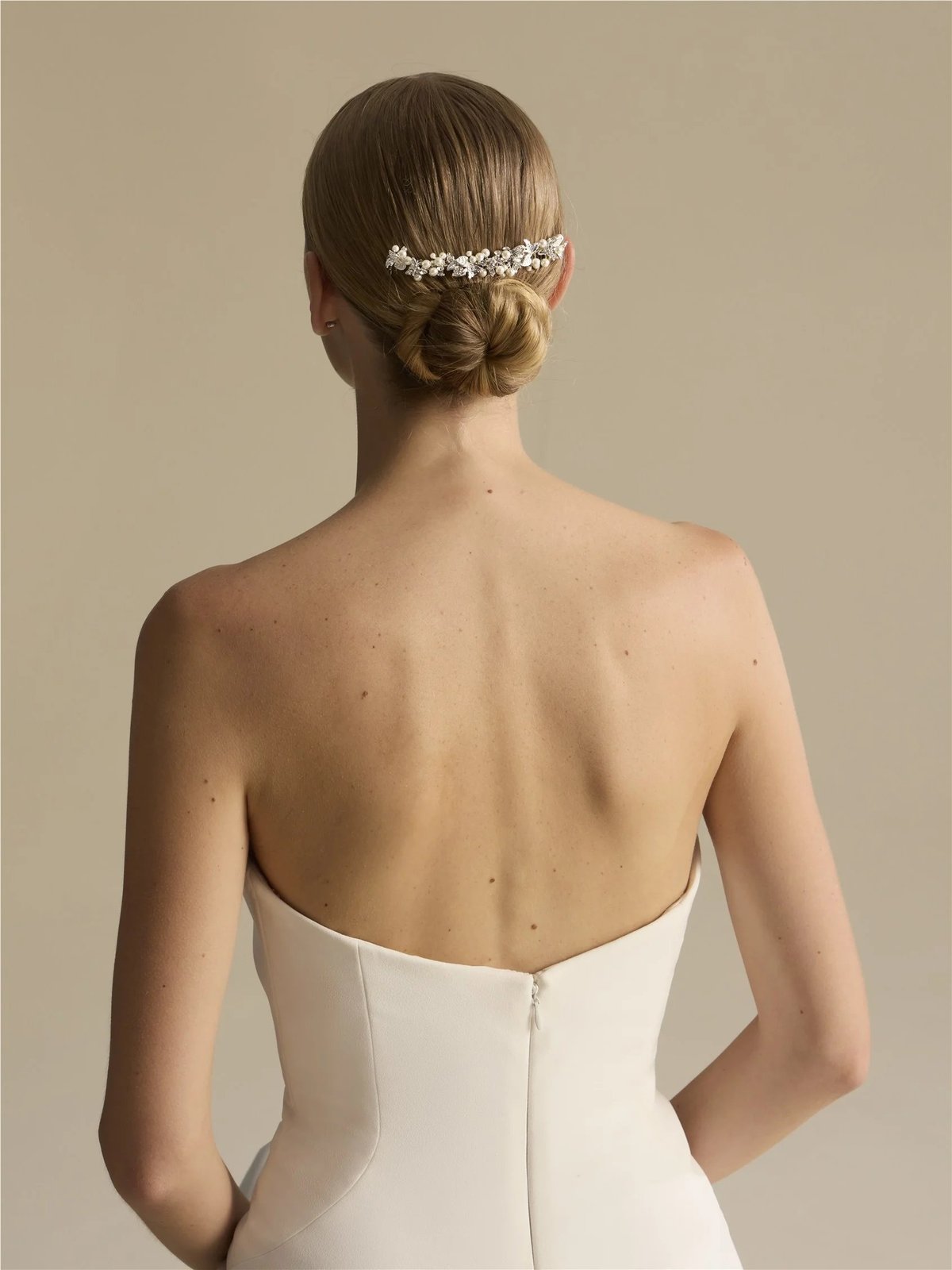 Back view of bride wearing white strapless wedding dress with beaded hair accessory and upswept hairstyle
